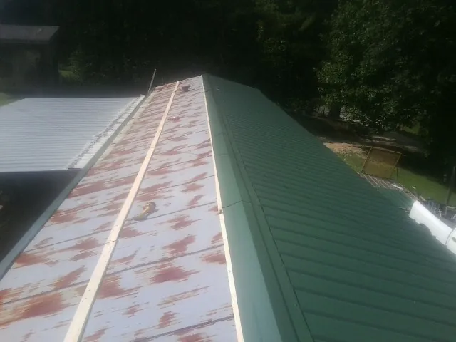Old rusted panels beside newly installed green metal roofing — Wind Damage Roof Repair by Roofing Brothers in Pedricktown