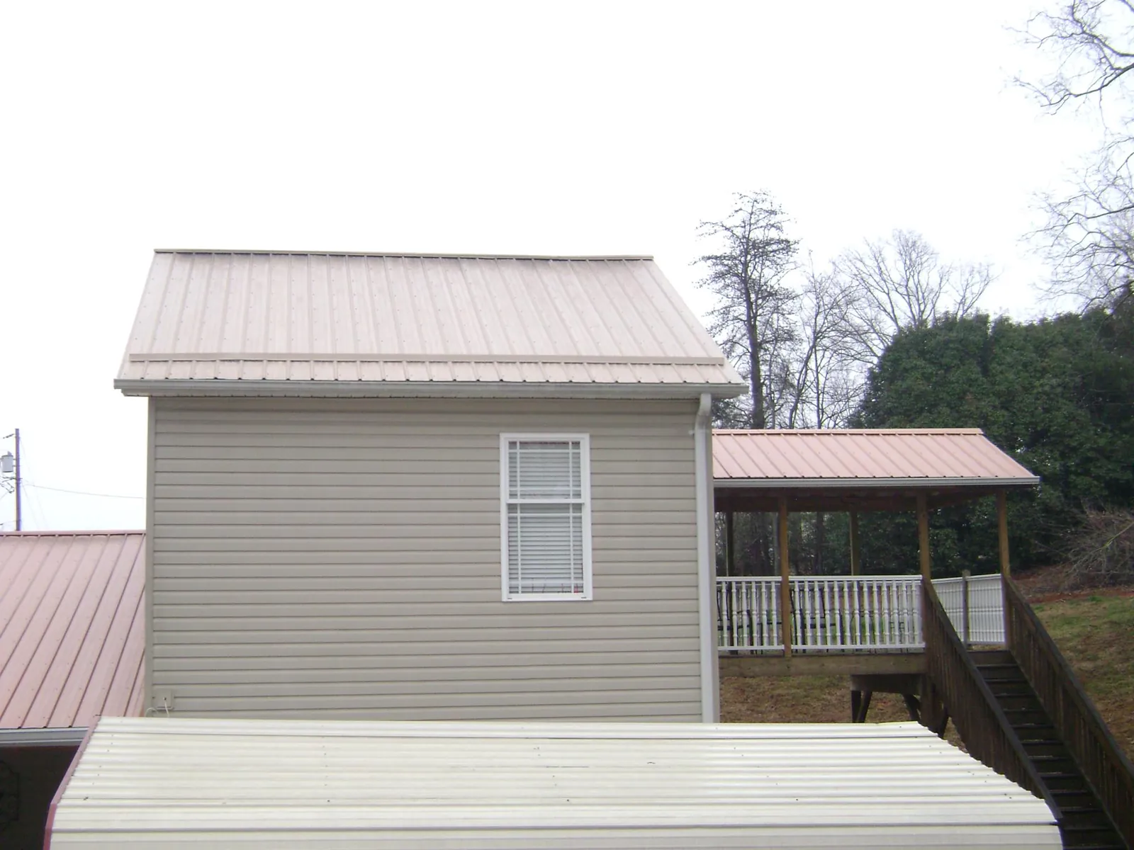 Tan metal roofs on a two story addition and attached porch, from a Roof Replacement job in Pedricktown